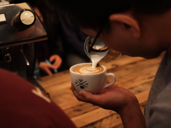 A latte artist completes his milk design. 