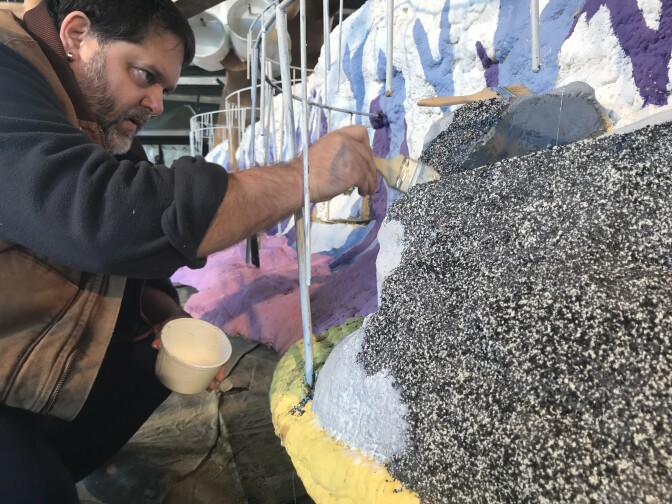 Volunteer Larry Geisz decorates part of the float with black and grey seeds
