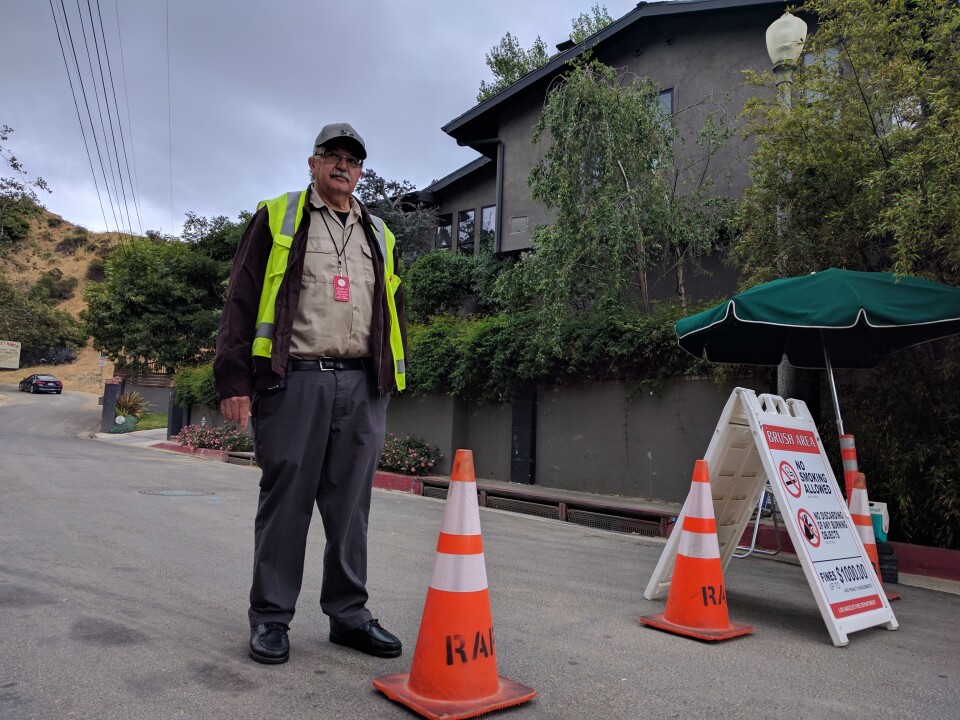 Kenneth Hansen with the LA Department of Recs and Parks stands guard at the former entrance to the Hollywood sign from Beachwood Dr. Since April 18th, the department has had to turn away tourists hoping to get close.