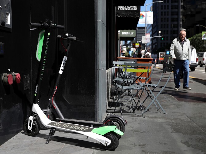Bird and Lime scooters sit parked in front of a building on April 17, 2018 in San Francisco.