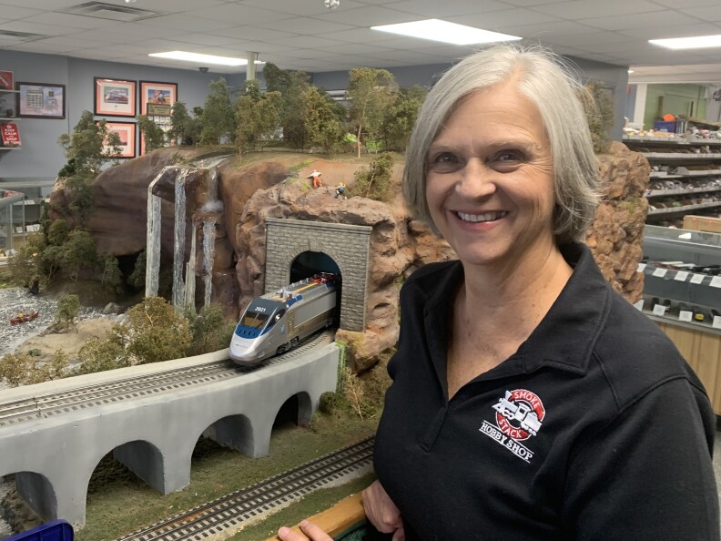 A woman stands in front of a model train display