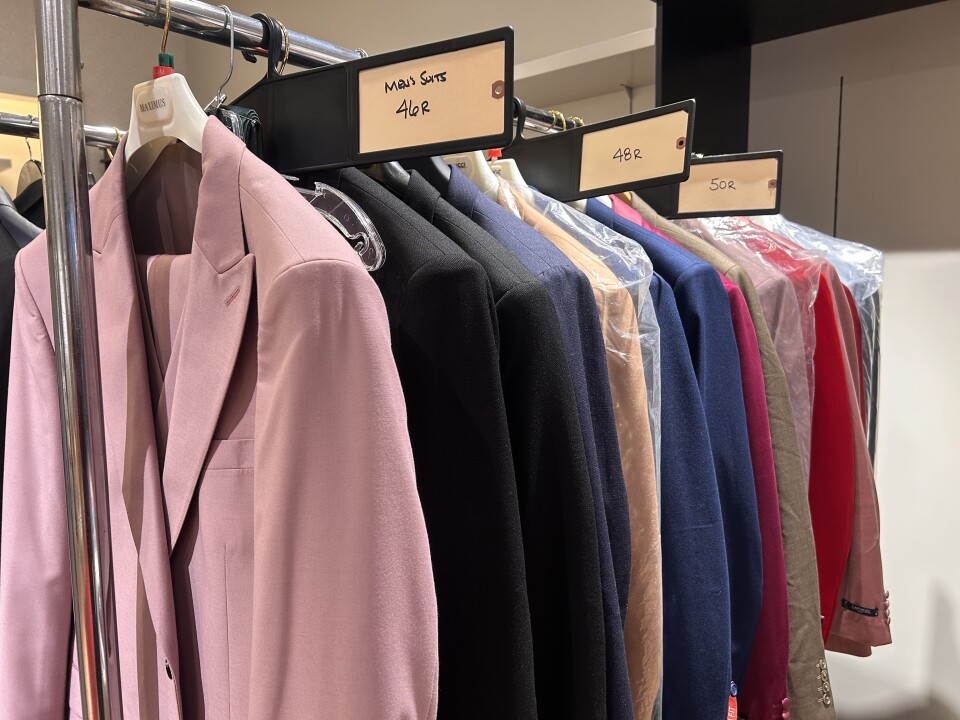 A metal rack with several different colored suit jackets hanging from the top.