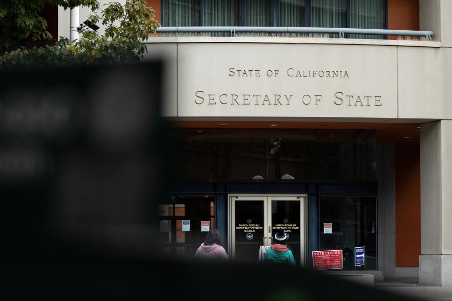 Two people walk toward the entrance of a building labeled "State of California Secretary of State."