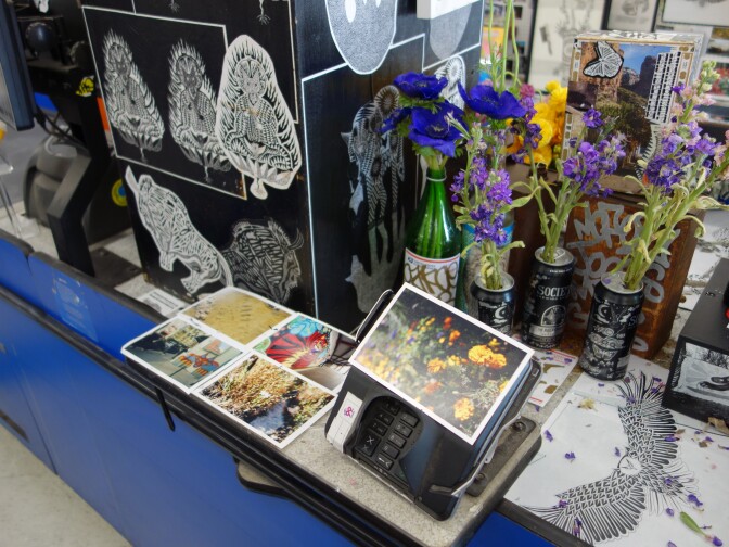 A supermarket checkout lane that's been covered with art, postcards and flowers.