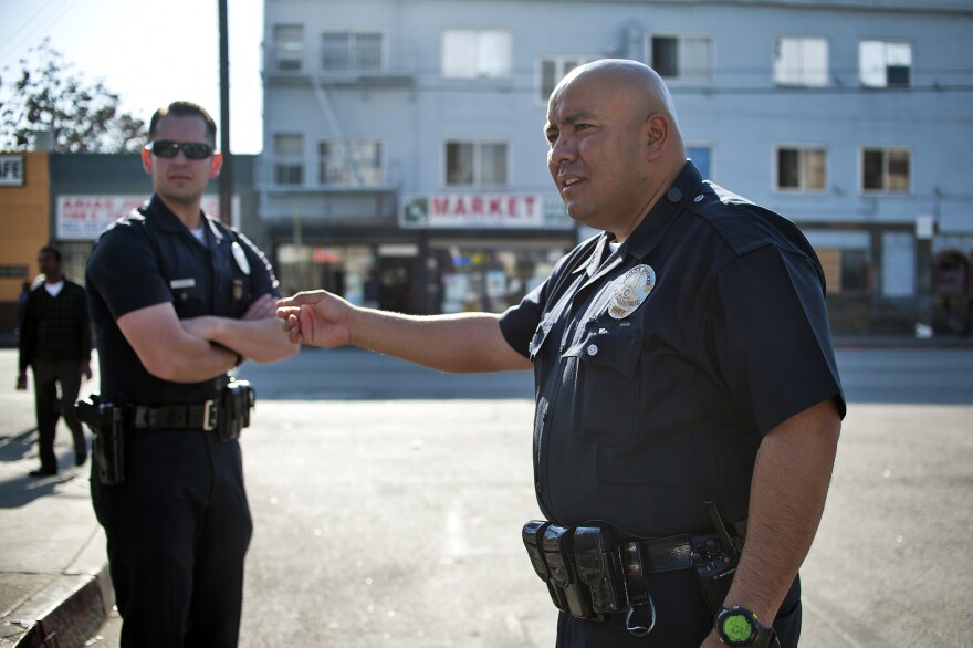 LAPD Officers William Allen, left, and Guillermo Espinoza talk with two people in an argument on the street. Allen and Espinoza are part of LAPD's central station where the body cameras will be tested out for 90 days.