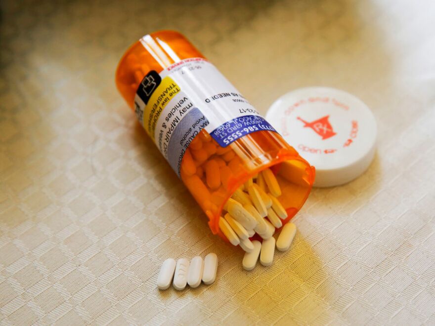 An open pill bottle has white pills