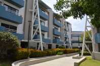 A three story apartment building is painted in blue and white.