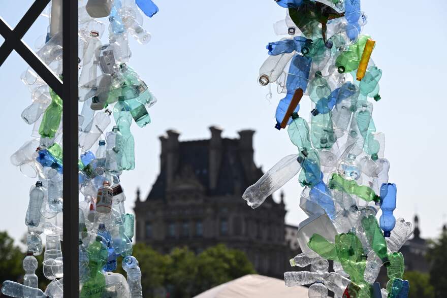 An array of clear, blue and green plastic bottles frame an old building in the background