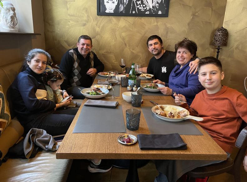 A family, including two children, seated around a large table at a restaurant.