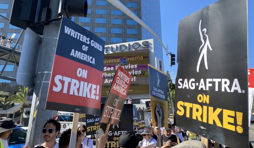 Hollywood strikers hold signs that say: "Writers Guild of America on Strike!" and "SAG-AFTRA on Strike!"