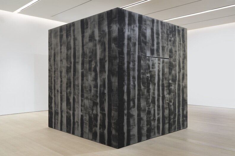 An art exhibition featuring a large cube made out of a variety of materials such as acrylic and aluminum.
