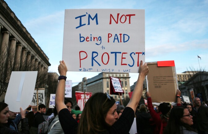 WASHINGTON, DC - FEBRUARY 08:  A demonstrator holds a sign reading 'I'm not being paid to protest" at a demonstration outside the White House against President Donald Trump's executive action to allow the Dakota Access Pipeline on February 8, 2017 in Washington, DC. The controversial project would carry oil from North Dakota to oil refineries and pipeline networks in the Midwest. Protesters say it would disturb indigenous burial grounds and possibly harm the environment. (Photo by Mario Tama/Getty Images)