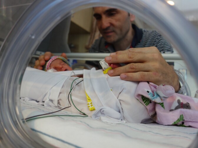 Saturnino Izquierdo, a new dad of premature triplets, holds the tiny foot of his daughter Francesca at Miller Children's Hospital, Nov. 24, 2016.
