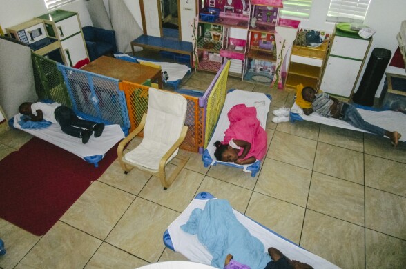 In this image, a group of four children are shown resting on small cots during naptime.