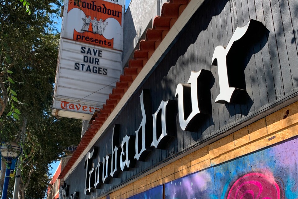 A black Troubadour sign below a marquee reading "SAVE OUR STAGES," above a bright graffiti mural.