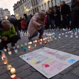 Persons light candles during a candle light vigil to the victims of the Paris attacks in Brussels' Molenbeek district, on November 18, 2015.