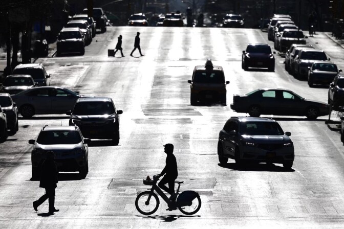 A cyclist riding across a busy street in New York city silhouetted against a cityscape 