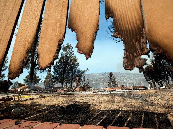 A burned-down home on Newview Road in Lake Hughes, seen through a burned fence.