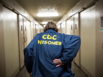 SAN LUIS OBISPO, CA - DECEMBER 20:  Frank Fuller, age 66, walks down the hall to his cell at California Men's Colony prison on December 20, 2013 in San Luis Obispo, California. Fuller is assisted by the Gold Coats program, a volunteer care program where healthy prisoners volunteer to take care of elderly prisoners who either need general assistance with mobility and every day life or who also struggle with Alzheimer's and dementia. The program, the first of it's kind in the country, has existed for approximately 25 years; there are currently 11 "Gold Coats." Fuller is serving a 35-years-to-life sentence; he has been incarcerated since 1990. He has been in the Gold Coats program for over six years. He says he is serving time for the murder of his third wife, who he says he shot with a rifle in a drunken rage after learning she had been having an affair with another man. He has been diagnosed with Post Traumatic Stress Disorder from serving five years in the Navy in the Vietnam War; he also has Hepatitis C. Fuller, who took shrapnel in his legs from a mortar round in Vietnam, says he held many different positions while fighting in Vietnam, including being a machine gunner; he says he still suffers occasional flash backs. He says has served one other sentence for murdering a man with a .45 gun in a fight. Between Vietnam and prison, he says he worked in the oil fields and in manufacturing. Fuller uses a cane to get around, and is constantly worried prison officials will move him to California Medical Facility, a prison for inmates with medical issues.  (Photo by Andrew Burton/Getty Images)