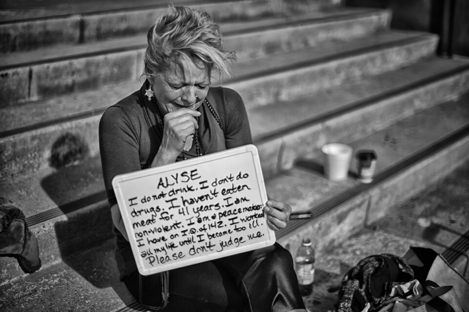 Van Nuys
Aylse Heggen, 56-years old, from Houston TX became homeless in Aug 2015 when her daughter she was living with moved back to TX and do to illness she  could not work. Aylse was sitting on some steps outside the Van Nuys City Hall building with another homeless woman. She is a very intelligent woman that is articulate and thoughtful. She told me that the woman that she was with was going to die because she had an untreated sexually transmitted disease that she got when she worked as a prostitute in the past. The woman with her would not speak to me and became slightly agitated when I tried to talk to her. 
Aylse told me that the thing that hurts the most is how people that are not homeless judge her. She believes that she is a good person and that people should give her a chance before passing judgment on her for being homeless. She dislikes how people watch her when she goes in to a store and how sometimes they ask her to leave because she is homeless. (video)

Sign: Alyse: “ I do not drink. I don’t do do drugs. I haven’t eaten meat for 41 years. I am non-violent. I am a peacemaker. I have an I.Q. of 142. I worked all my life until I became too ill. Please don’t judge me”
 (Photo by Hans Gutknecht/Los Angeles Daily News)
