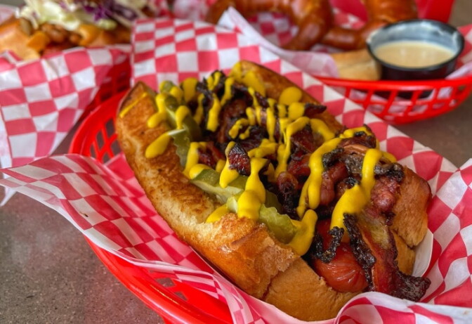 A bratwurst on a bun with bright yellow mustard drizzled on top