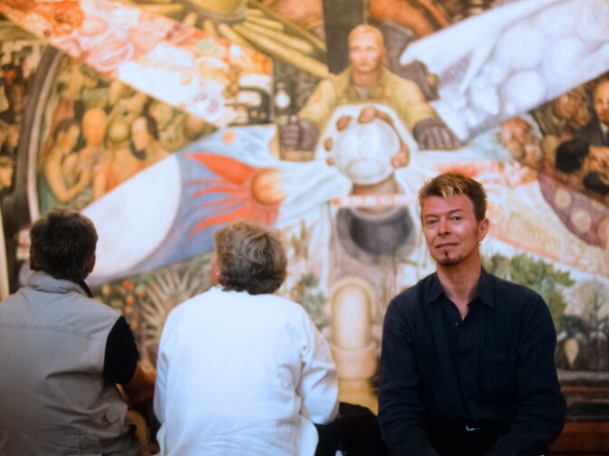David Bowie poses in front of the Diego Rivera painting "Crossroads Man" at the Palace of Fine Arts during his 1997 trip to Mexico. 