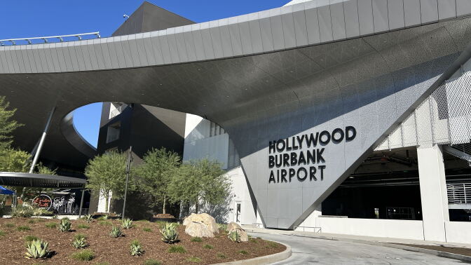 A wide view of the new Hollywood Burbank Airport sign that's connected to a large rounded overhang across the facility. 