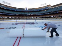 A worker rolls up mylar that protected a hockey rink at Dodger Stadium from daytime temperatures in the high 70s Fahrenheit, as preparations continue for the upcoming 2014 NHL Stadium Series hockey game in Los Angeles, Wednesday, Jan. 22, 2014. The Los Angeles Kings and Anaheim Ducks will play outdoors at Dodger Stadium next Saturday, Jan. 25th. (AP Photo/Nick Ut)