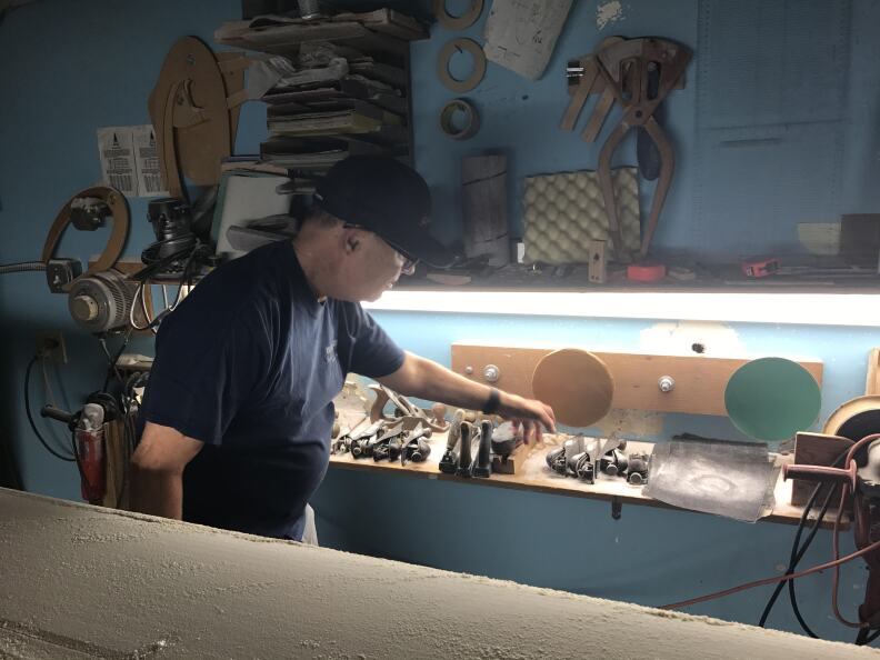 Rich Harbour reaches for the tools that help him smooth and shape the surfboard decks to his specficiations.
