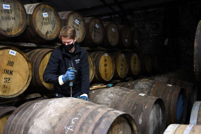 Employee Matthew Coulson poses for a photograph with whisky casks in the bonded warehouse at The Glenturret Distillery in Crieff, central Scotland, on February 26, 2021. - It has survived world wars, Prohibition and The Great Depression but this may very well be the toughest time yet for Scotland's oldest whisky maker. The Glenturret Distillery, located on the banks of the River Turret two miles (3.2 kilometres) northwest of the town of Crieff, was established in 1763 and is a popular stop for whisky enthusiasts. "It has been a really tough period for us with Covid, US tariffs and Brexit as well," the distillery's managing director, John Laurie, told AFP. (Photo by Andy Buchanan / AFP) / TO GO WITH AFP STORY BY Stuart GRAHAM (Photo by ANDY BUCHANAN/AFP via Getty Images)