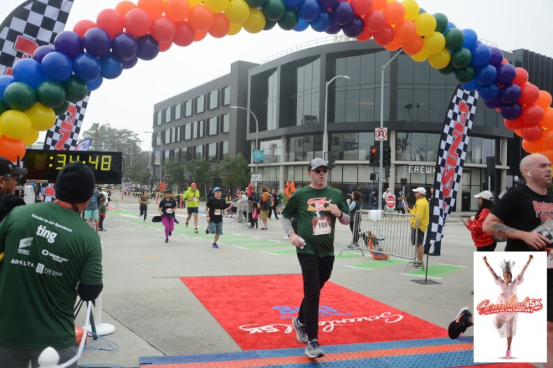 People race to the finish line with a rainbow balloon arch for the Screenland 5k race.