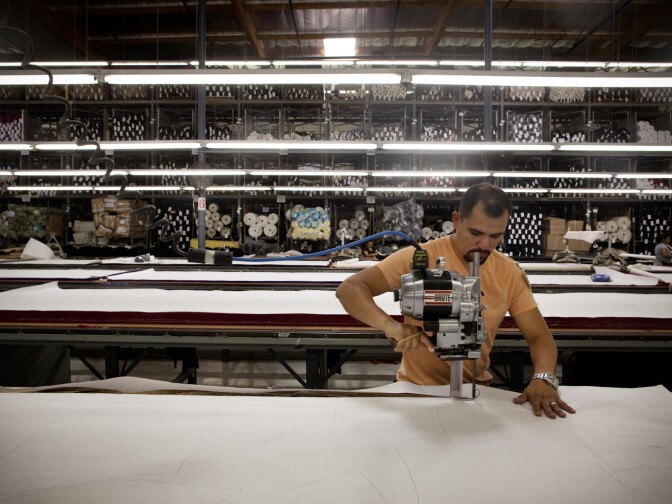 Jose Garcia, a manager at Karen Kane, trims the edges of the marker -- a  long sheet of paper with the outlines of the apparel components that will be cut by a computerized machine.