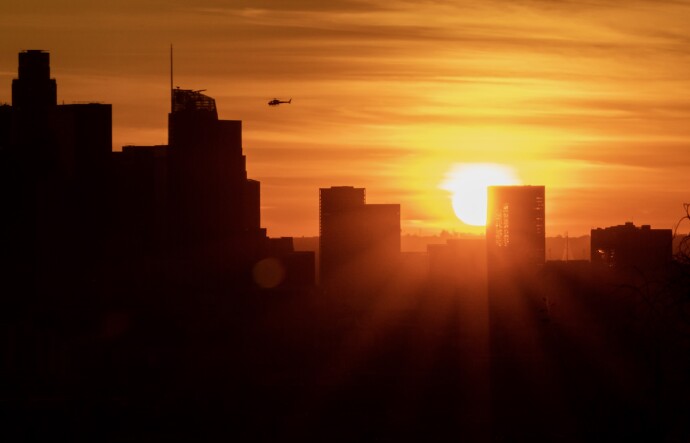The sun sets behind buildings, leaving them in silhouette, in downtown L.A. during last year's winter solstice.