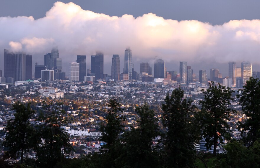 The downtown Los Angeles skyline with low clouds overhead.