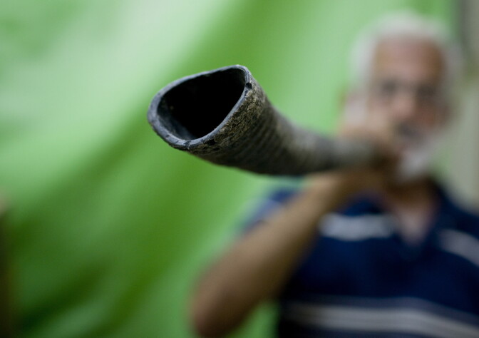 A man blows a shofar, a musical instrument used in Jewish religious ceremonies made from the horn of a ram.