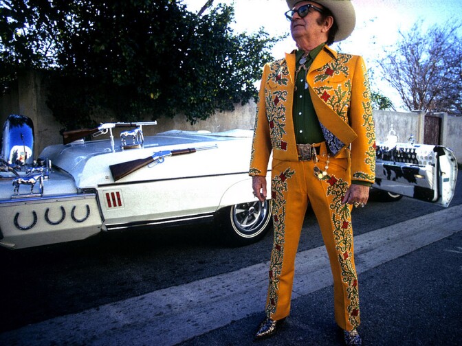 Nudie Cohn posing in front of one of his custom Nudie Mobiles, a Pontiac Bonneville convertible made for Hank Williams Jr.