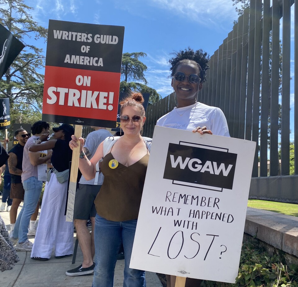 Two picketers hold signs outside the Warner bros. lot 