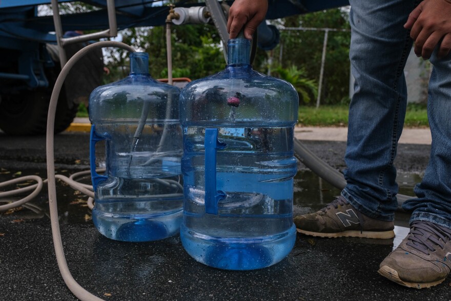 Residents of Orocovis line up at the community sports coliseum. People like Jesus "Tito" Colón are using any kind of container — gallon jugs, cisterns — to fill with potable water.