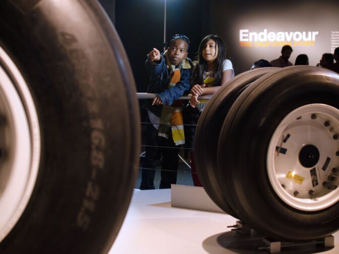 Two children look at the tires from STS-134, space shuttle Endeavour's last mission, during a preview of Endeavour: The California Story exhibition at the California Science Center.
