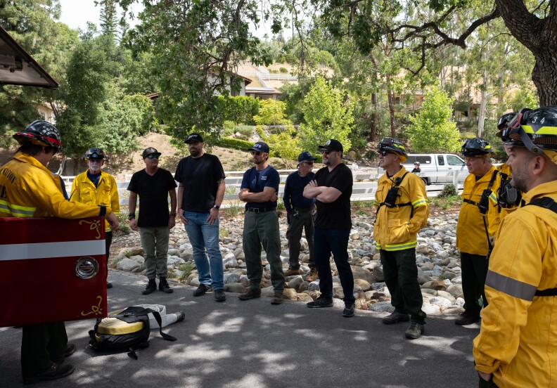 People standing around in fire gear as well as normal clothes.