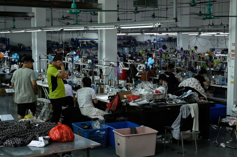 A scene of a garment factory that supplies fast-fashion retailer Shein. Dozens of workers can be seen either standing or at sewing machines.