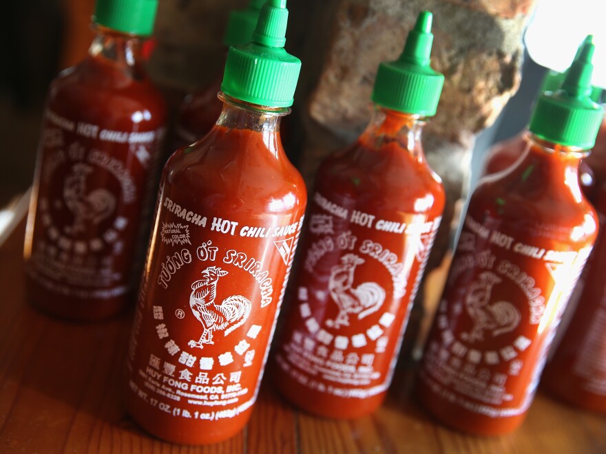 Bottles of sriracha hot sauce on a table.