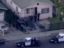 Police surround a home where they believe an armed suspect shot at an LAPD officer and a county probation officer in South Los Angeles on Tuesday night.