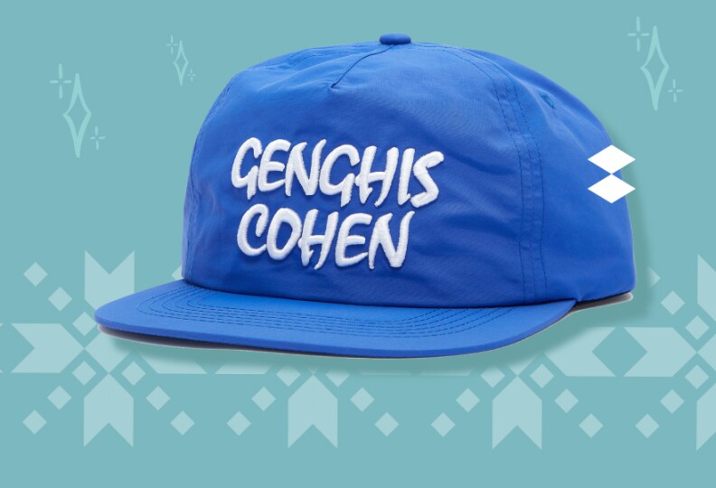 A blue cap with white lettering that reads Genghis Cohen