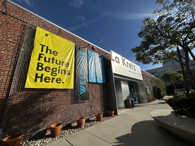 A wide angle shot of the outside of a brick building with a large yellow sign that reads "The future begins here." 