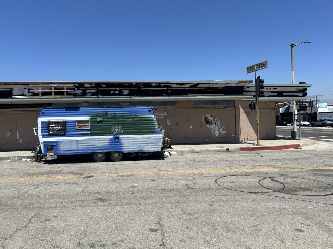 a blue rv against a brown building 