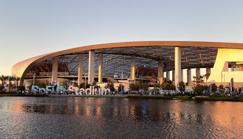 Photo of SoFi Stadium's sweeping canopy roof as seen from across a lake.