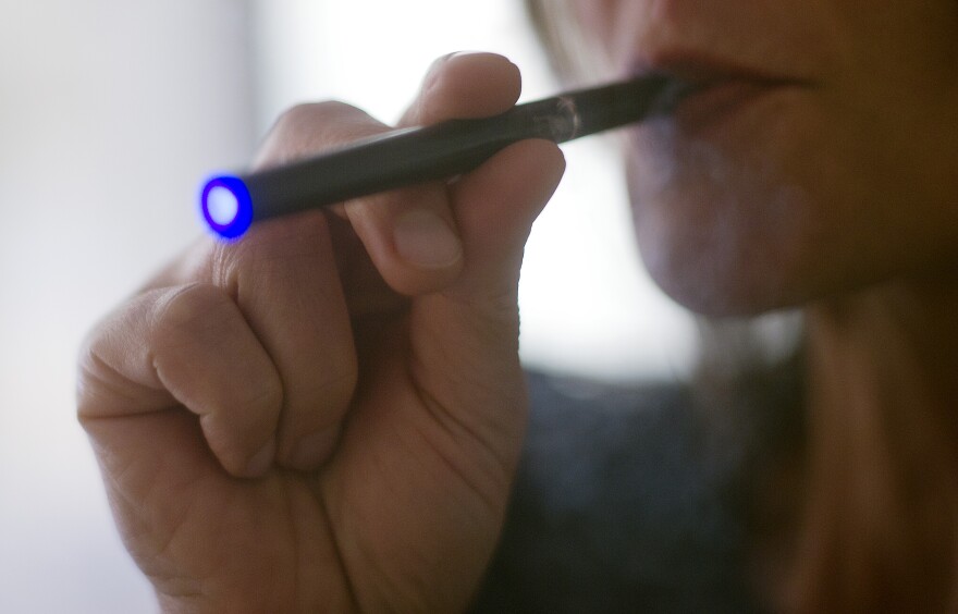 This September 25, 2013 photo illustration taken in Washington, DC, shows a woman smoking an 'Blu' e-cigarette. In Los Angeles Wednesday, the city council voted unanimously to regulate them much the same way as tobacco products.
