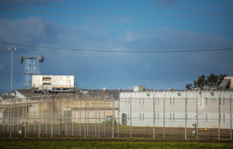 A white-colored building with wire fencing around it's perimeter. The building is a youth correctional facility in California.