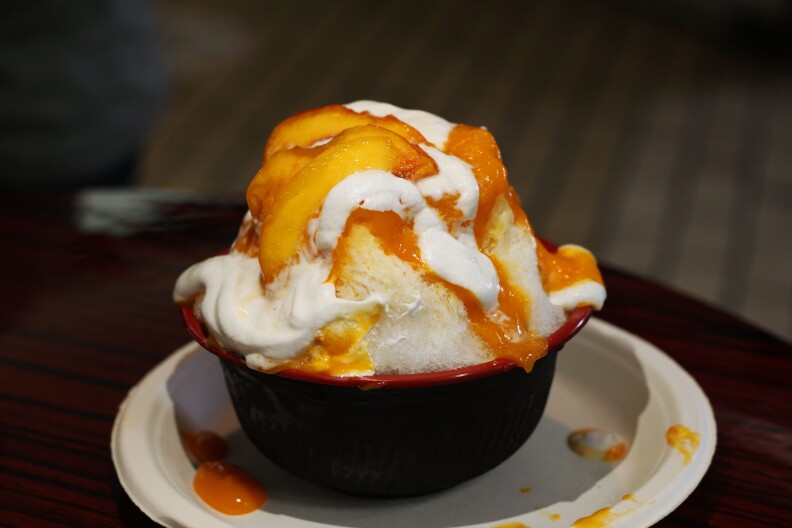 sliced peaches on a mound of white cream and shaved ice